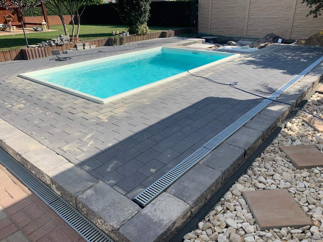 Blick in ein klares Schwimmbecken mit gepflasterter Umrandung